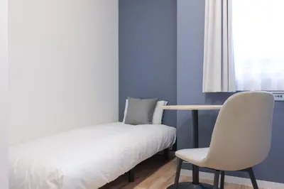 a bedroom with a bed and a chair and a window at CH RESiDENCE \u4e21\u56fd in Tokyo