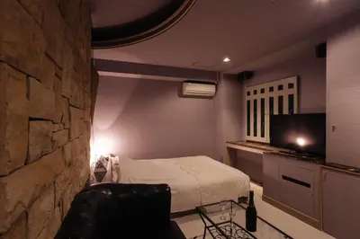 a bedroom with a bed and a stone wall at Hotel en \u30db\u30c6\u30eb \u30a8\u30f3-Adult Only- in Tokyo
