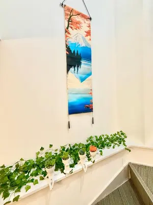 a row of potted plants on a wall with a painting at Tokyo Life hotel in Tokyo
