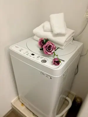 a washing machine with towels and flowers on top of it at Japan House Ikebukuro Honcho in Tokyo