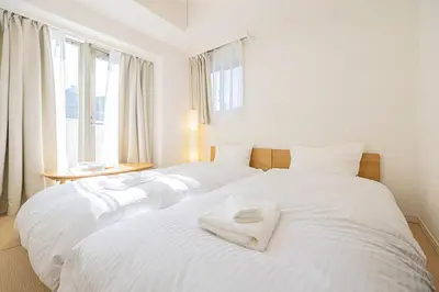 two beds in a bedroom with white sheets and towels at SQ312-5 mins Shibuya Station JR Yamanote - Max 2 in Tokyo