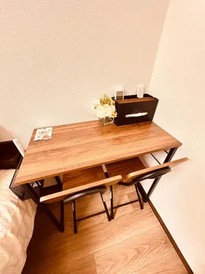a wooden table with flowers on it next to a bed at \u65b0\u5bbf\u6700\u4e2d\u5fc3 \u6b4c\u821e\u4f0e\u753a \u4e1c\u65b0\u5bbf5\u5206 \u65b0\u5bbf9\u5206 \u6700\u591a4\u4eba \u76f4\u8fbe\u6e0b\u8c37\u539f\u5bbf\u4e0a\u91ce\u79cb\u8449\u539f in Tokyo