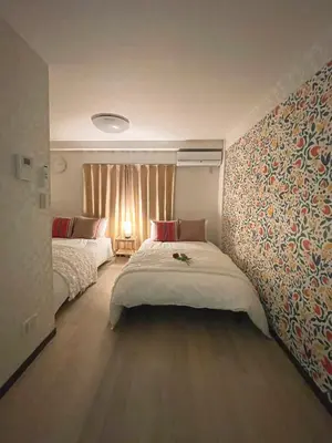 a bedroom with two beds and a wall with wallpaper at #3 \u65b0\u5bbf\u307e\u30672\u5206! \u6e05\u6f54\u3067\u5b89\u5168\u306a\u90e8\u5c4b! WiFi\u7121\u6599! in Tokyo