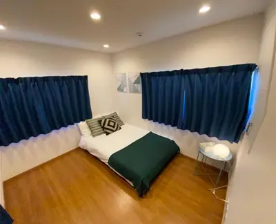 a bedroom with a bed and two blue curtains at Shin-Nakano House in Tokyo