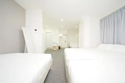 two white beds in a white room with a desk at GLOU Koiwa Tokyo - Economic APT in a Japanese Local Shopping Street, with Direct Access to Shinjuku & Akihabara in Tokyo
