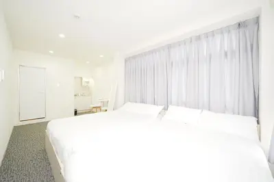 a white bedroom with a large bed and a window at GLOU Koiwa Tokyo - Economic APT in a Japanese Local Shopping Street, with Direct Access to Shinjuku & Akihabara in Tokyo