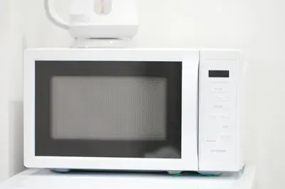 a white microwave oven sitting on top of a counter at GLOU Koiwa Tokyo - Economic APT in a Japanese Local Shopping Street, with Direct Access to Shinjuku & Akihabara in Tokyo