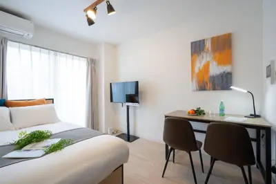 a bedroom with a bed and a desk with chairs at \u30a6\u30a4\u30f3\u30d9\u30eb\u30bd\u30ed\u6771\u84b2\u7530 in Tokyo