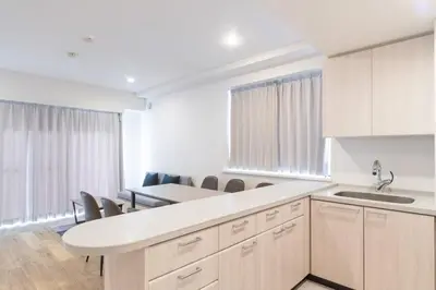 a kitchen with white cabinets and a table and chairs at \u5e83\u5c3e\u30a4\u30fc\u30b9\u30c8 in Tokyo