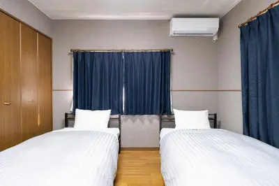two beds in a room with blue curtains at The \u30cd\u30b3\u30b6\u30cd HAUS in Urayasu