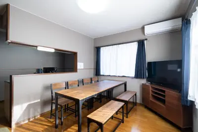 a dining room with a table and chairs and a flat screen tv at The \u30cd\u30b3\u30b6\u30cd HAUS in Urayasu