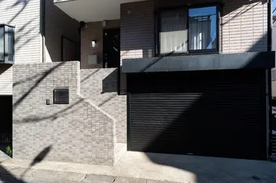 a black garage door on a brick building at The \u30cd\u30b3\u30b6\u30cd HAUS in Urayasu