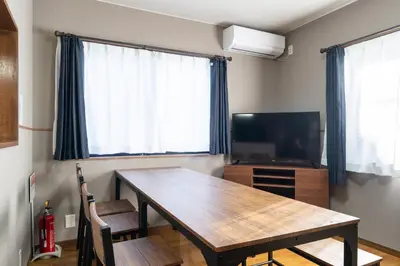 a dining room with a table and a television at The \u30cd\u30b3\u30b6\u30cd HAUS in Urayasu