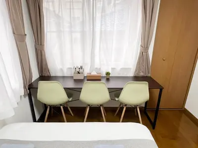 a table with three chairs in front of a window at nestay villa tokyo akasaka in Tokyo