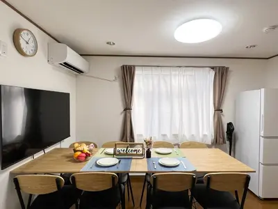 a dining room with a table with chairs and a television at nestay villa tokyo akasaka in Tokyo
