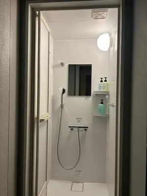 a bathroom with a shower with a sink and a mirror at Yoroi Asakusa Hotel in Tokyo