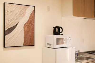 a microwave on top of a refrigerator in a kitchen at SUNRISE STAY Asakusa in Tokyo