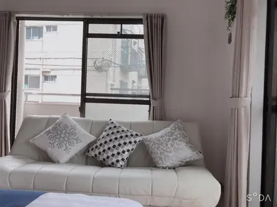 a white couch with pillows in a room with a window at kitashijyuku in Tokyo