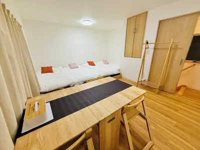 a room with two beds and a wooden table at asakusa \u5343\u675f in Tokyo
