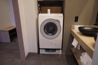 a washing machine in the corner of a bathroom at GRAND MONday GINZA in Tokyo