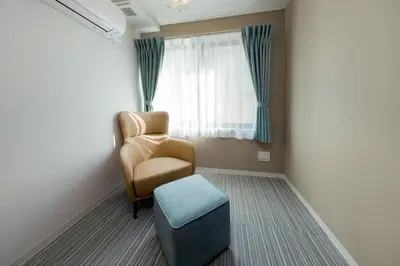 a chair and a stool in a room with a window at Ra Grande by Tranova in Tokyo