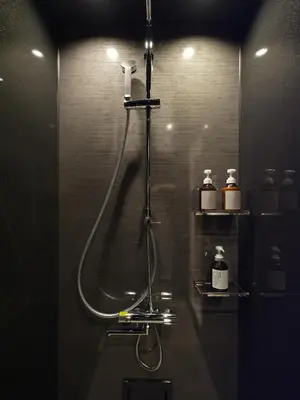 a bathroom with a shower with a hose and two bottles at T-home\u96c6 T-home SHU in Tokyo