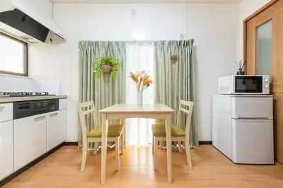 a kitchen with a table with chairs and a microwave at \u4e2d\u91ce\u65b0\u6a4b\u99c5\u5f92\u6b692\u5206 \u65b0\u5bbf\u99c5 in Tokyo