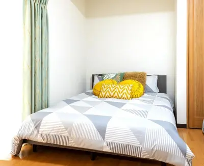 a bedroom with a bed with yellow and blue pillows at \u4e2d\u91ce\u65b0\u6a4b\u99c5\u5f92\u6b692\u5206 \u65b0\u5bbf\u99c5 in Tokyo