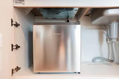 a stainless steel refrigerator in a kitchen under a sink at SAIEI Hotel in Tokyo