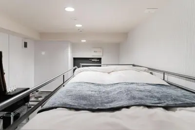 a large bed in a room with white walls at SAIEI Hotel in Tokyo