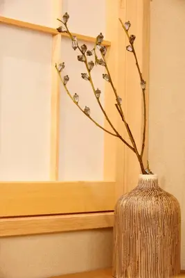 a vase with a branch in front of a window at MKG HOTEL Asakusa in Tokyo