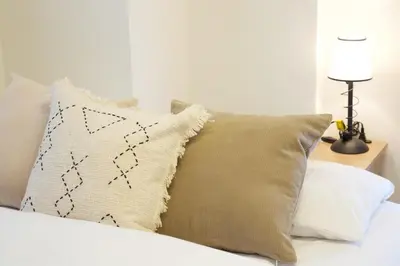 a white bed with a pillow and a table with a lamp at BAi\u6b4c\u821e\u4f0e\u753a2\u4e01\u76ee in Tokyo