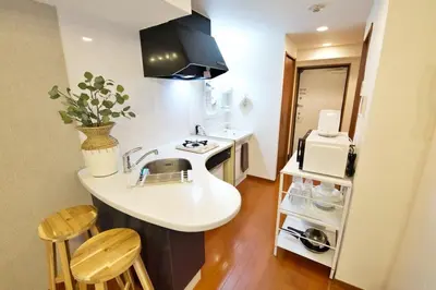 a kitchen with a sink and a counter with chairs at BAi\u6b4c\u821e\u4f0e\u753a2\u4e01\u76ee in Tokyo