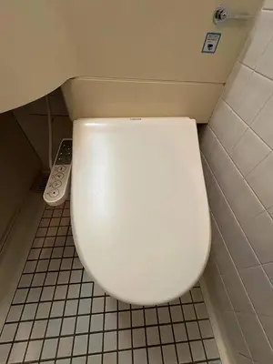 a white toilet in a bathroom with a remote control at \u65e5\u97d3\u30de\u30f3\u30b7\u30e7\u30f3 in Tokyo