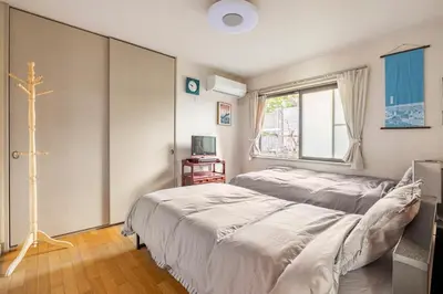 a bedroom with two beds and a cross on the wall at GP House in Tokyo