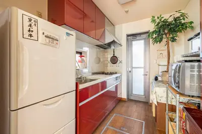 a kitchen with red cabinets and a white refrigerator at GP House in Tokyo