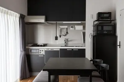 a small kitchen with black cabinets and a table at NIYS apartments 56type in Tokyo