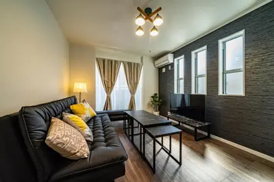 a living room with a black leather couch and a table at Kokoon Hotel Yotugi in Tokyo