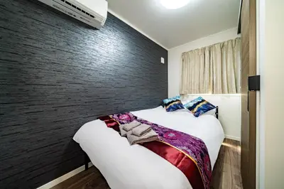 a bedroom with a bed and a wall at Kokoon Hotel Yotugi in Tokyo