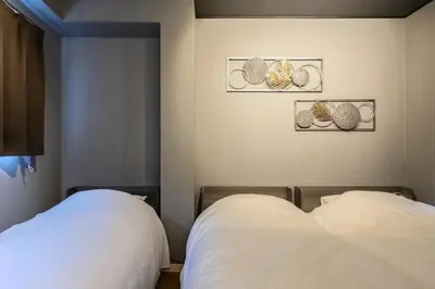 a bedroom with two beds and two pictures on the wall at Sumu Hotel Shinjuku in Tokyo