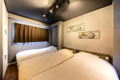 two beds in a room with a window at Sumu Hotel Shinjuku in Tokyo