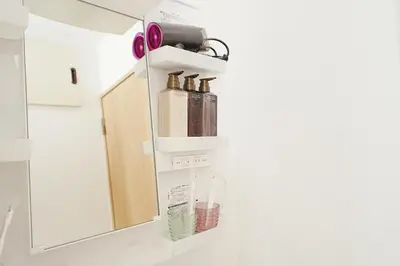 a bathroom with a mirror and some bottles on a shelf at Tokyo RIRIARU HOTEL \u65b0\u5fa1\u5f92\u753a in Tokyo