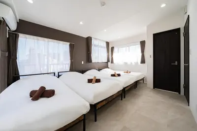 a row of beds in a room with windows at Kokoon Hotel Yahiro in Tokyo