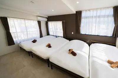 two beds in a room with white sheets at Kokoon Hotel Yahiro in Tokyo