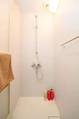 a bathroom with a shower with red bottles on the floor at Kokoon Hotel Yahiro in Tokyo