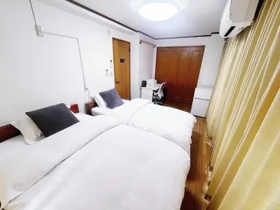 a bedroom with two beds with white sheets at \u70df\u96e8\u8f69 203 in Tokyo
