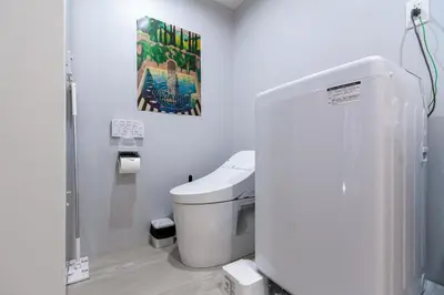 a bathroom with a toilet and a painting on the wall at Mi-HOTEL OTSUKA in Tokyo