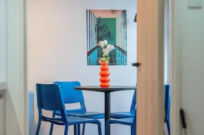 a table with blue chairs and a vase with flowers at Mi-HOTEL OTSUKA in Tokyo