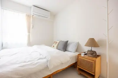 a white bedroom with a bed and a lamp on a night stand at Cloud Nine Apartment Sky Tree in Tokyo