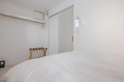 a white bedroom with a white bed and a window at Ikebukuro 3 Chome in Tokyo